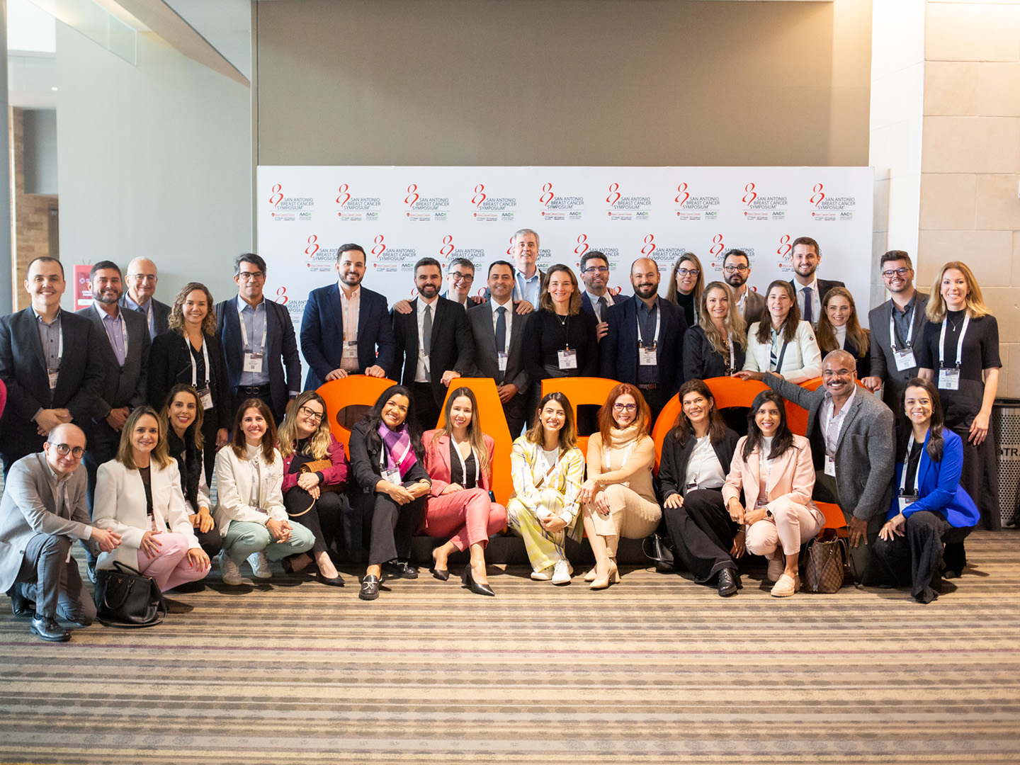 Attendees pose with the SABCS logo at the 2024 Symposium.
